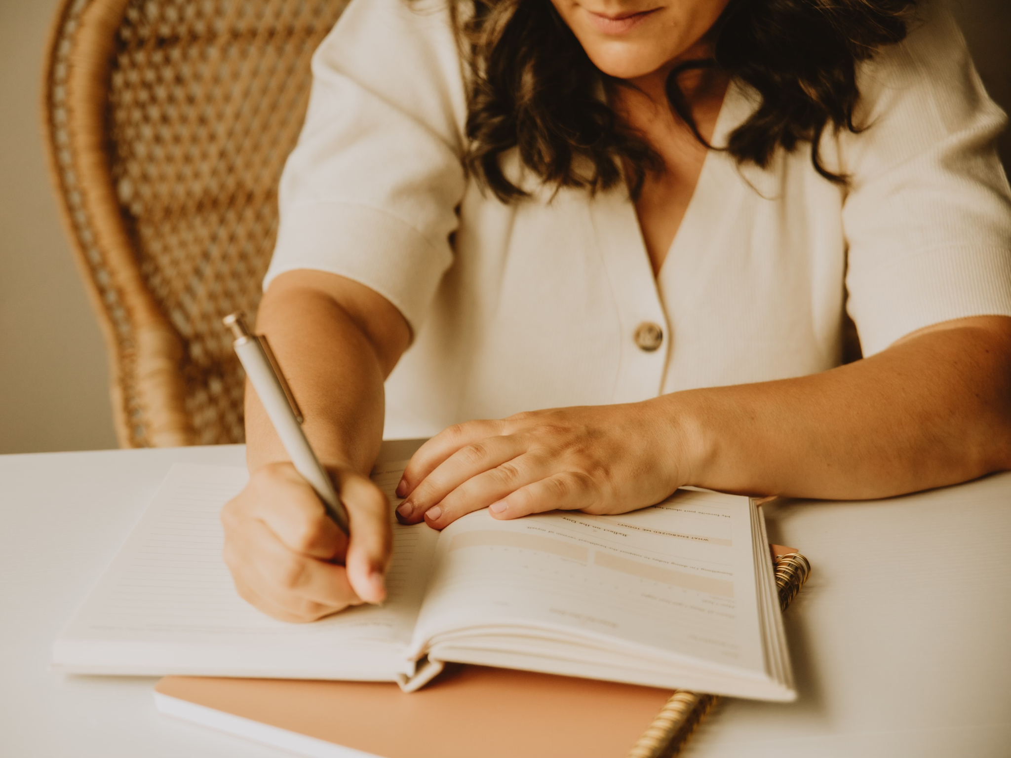A mother writes in a notebook while planning simple, story-led learning experiences for her family.