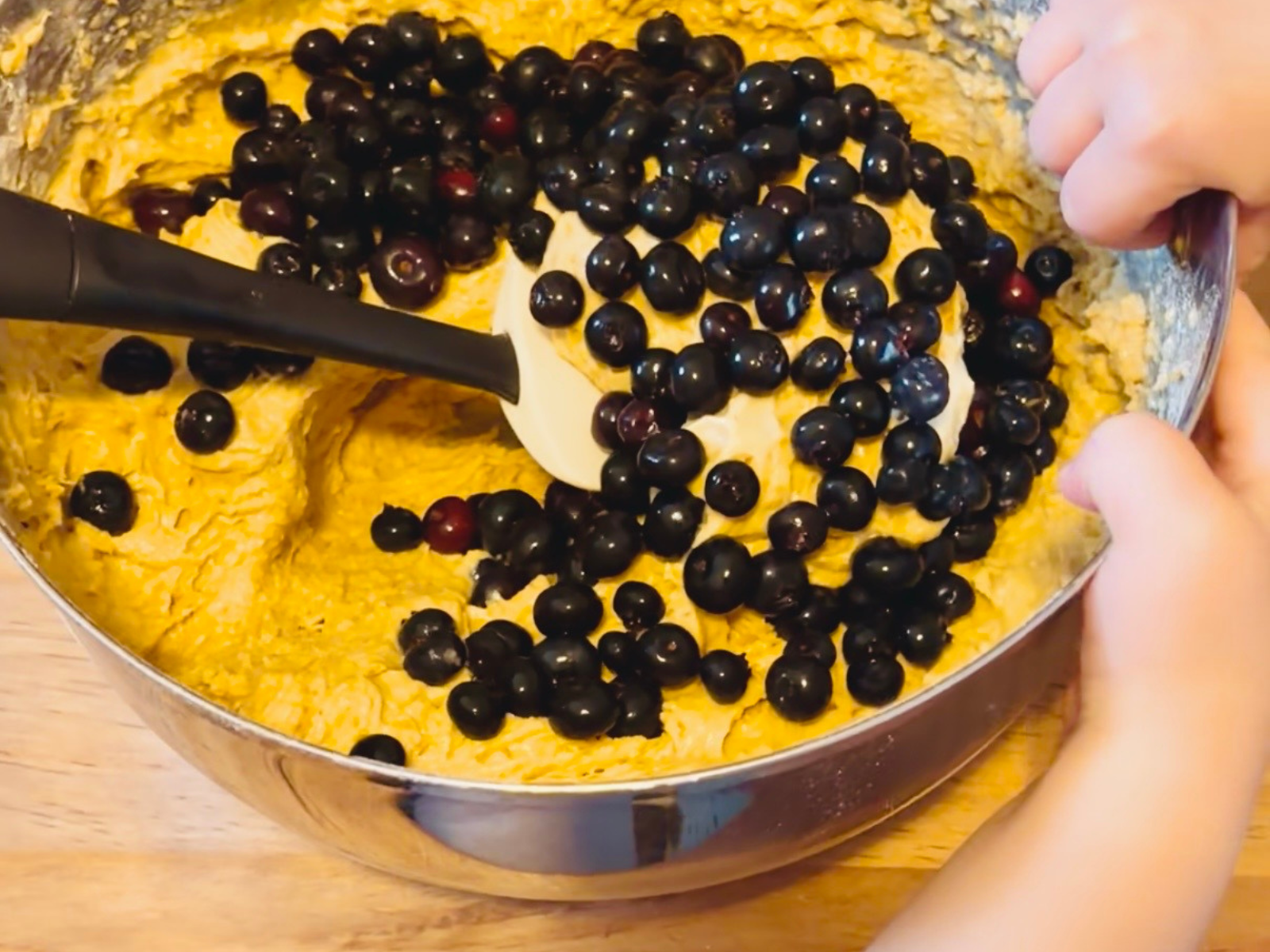 Child adding blueberries to mixing bowl during Blueberries for Sal inspired cooking activity, part of a gentle literature-based homeschool curriculum for young children