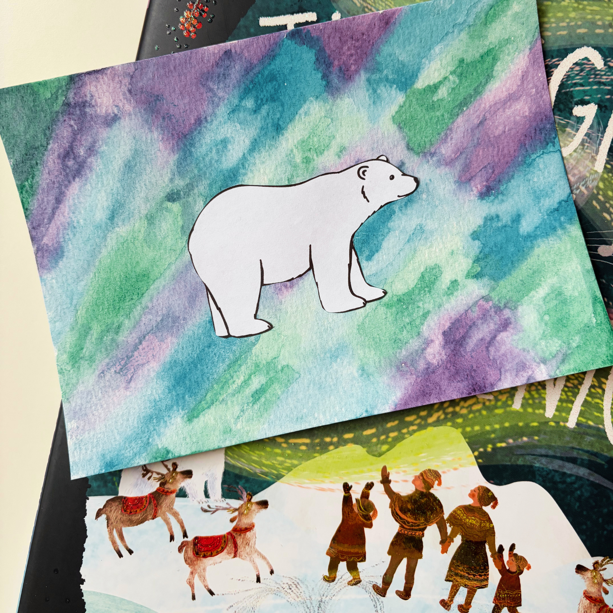 Child painting a winter background and creating a polar bear silhouette craft from the Snowy Days & Polar Ways preschool curriculum.