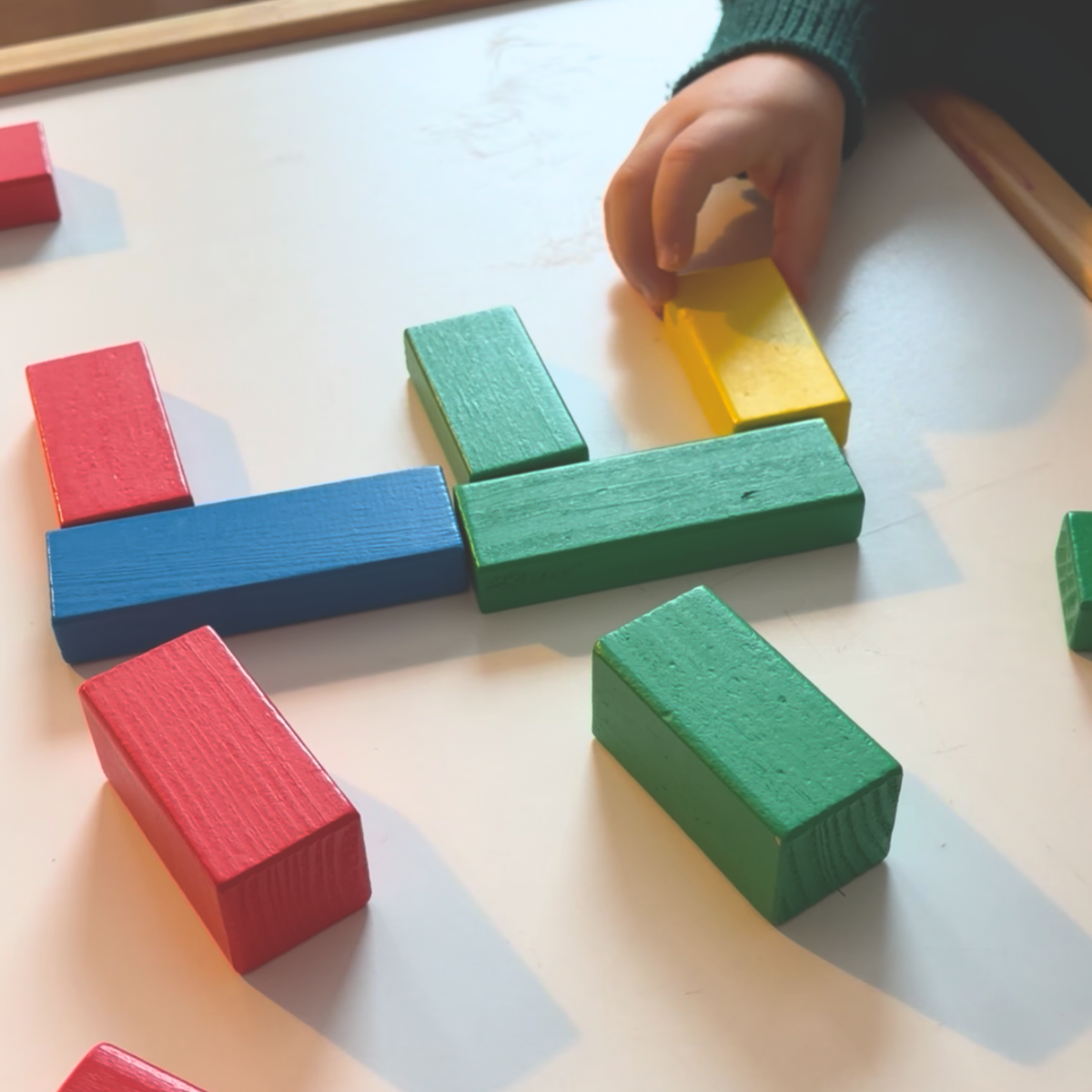 Child building with colorful wooden blocks during an An Extraordinary Egg story activity.