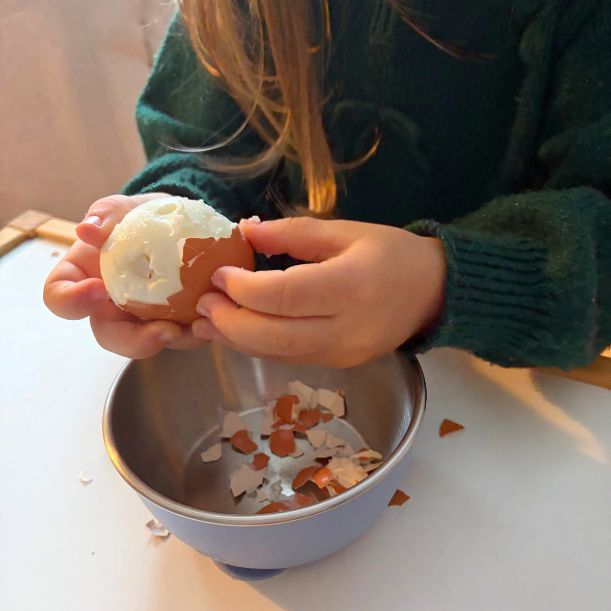 Child peeling an egg practicing hand-on life skills inspired by An Extraordinary Egg.