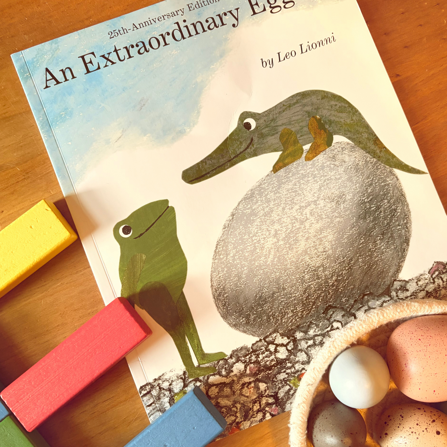 An Extraordinary Egg by Leo Lionni styled with wooden blocks and pretend eggs for preschool learning.