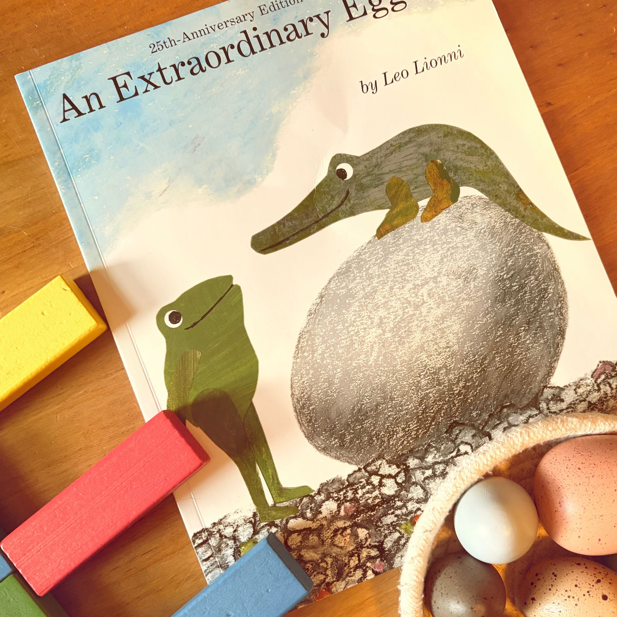 An Extraordinary Egg by Leo Lionni styled with wooden blocks and pretend eggs for preschool learning.