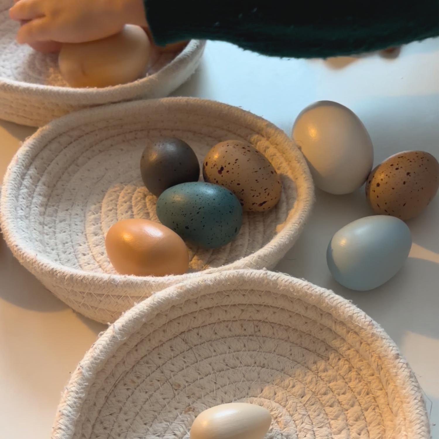 Child sorting colorful pretend eggs into baskets during a preschool math activity inspired by An Extraordinary Egg.