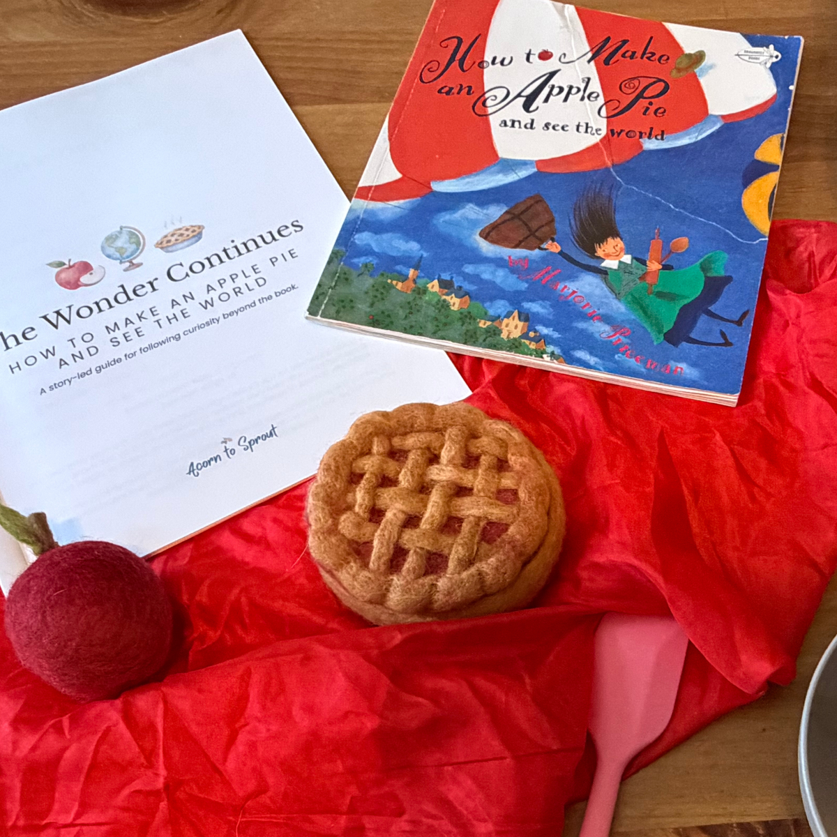 How to Make an Apple Pie and See the World picture book with The Wonder Continues guide, felt apple pie, apple, and red play silk