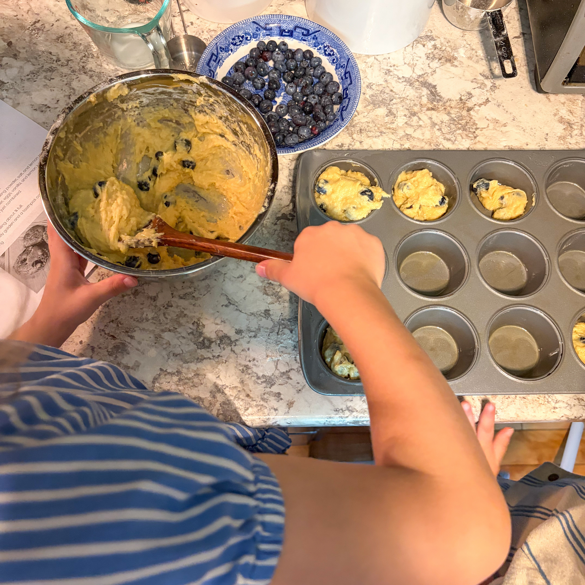 Child making blueberry muffins as a hands-on activity inspired by Blueberries for Sal.