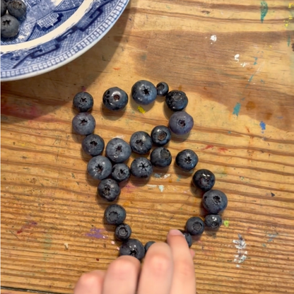 Child arranging blueberries into the number eight for a simple preschool math activity.