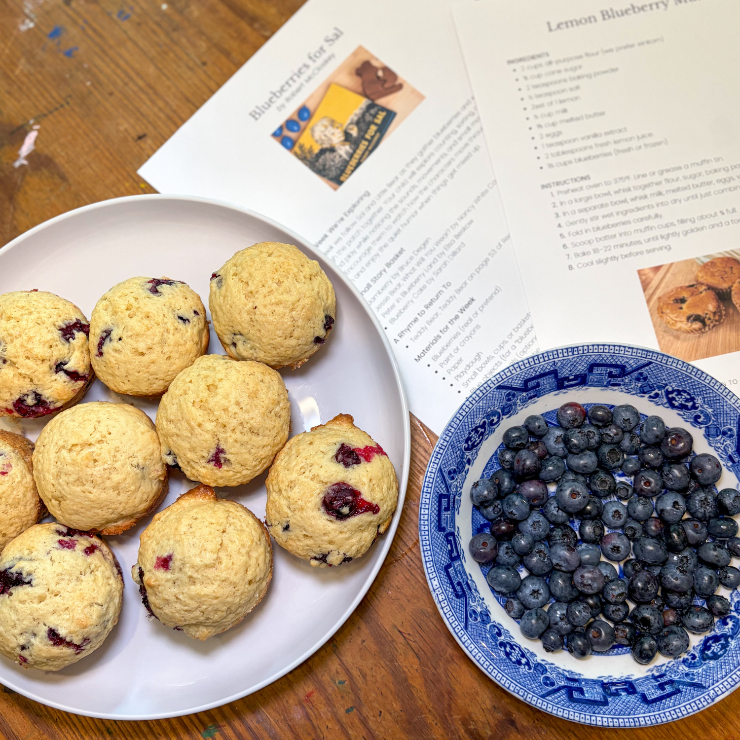 Homemade blueberry muffins, fresh blueberries, and Acorn to Sprout learning guide pages for Blueberries for Sal.