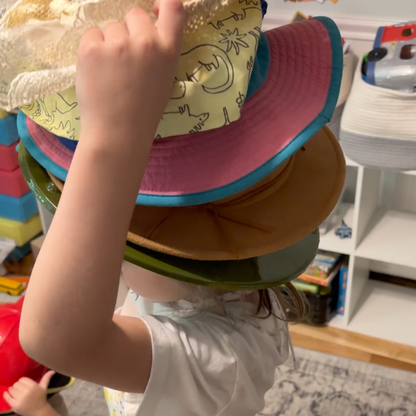 Child stacking colorful hats during pretend play inspired by Caps for Sale.