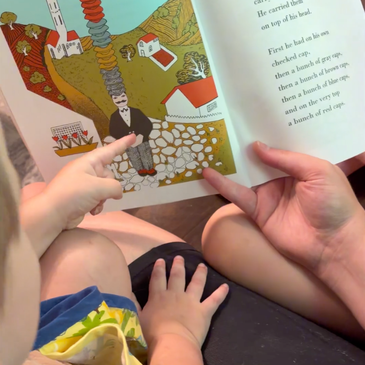 Adult and young children reading Caps for Sale together and pointing to the illustrations.