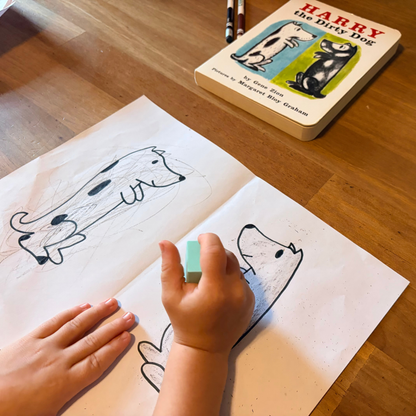 Child drawing dogs during a preschool art activity inspired by Harry the Dirty Dog.