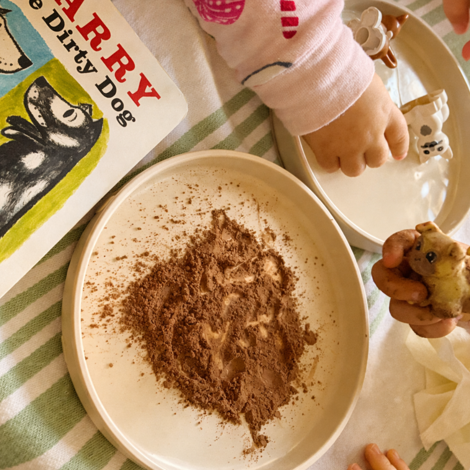 Harry the Dirty Dog book beside a sensory tray with cocoa powder and small hands exploring texture as part of a gentle preschool activity.