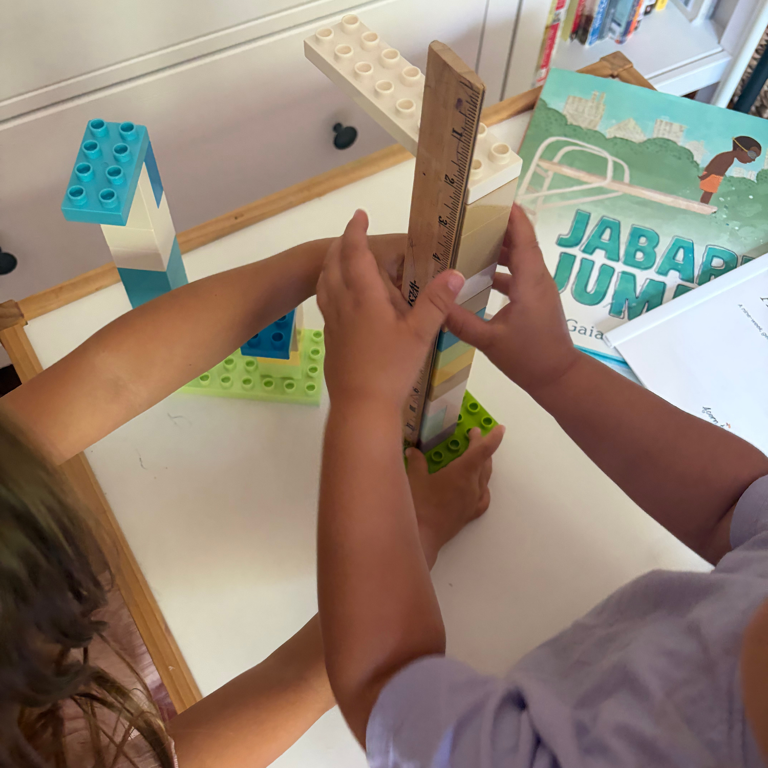Children measuring a block structure with a ruler during a Jabari Jumps preschool activity.