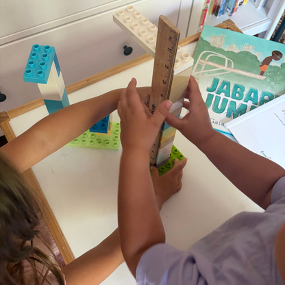 Children measuring a block structure with a ruler during a Jabari Jumps preschool activity.