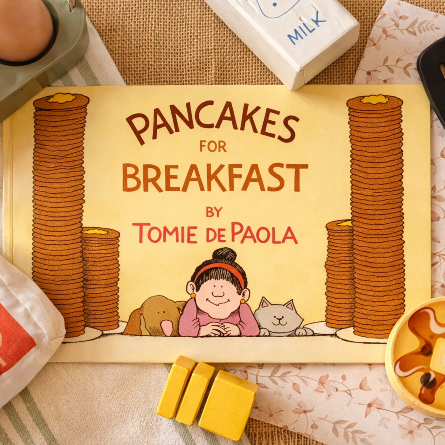 Pancakes for Breakfast by Tomie dePaola displayed with wooden play food, illustrating a literature-based preschool reading and activity invitation.