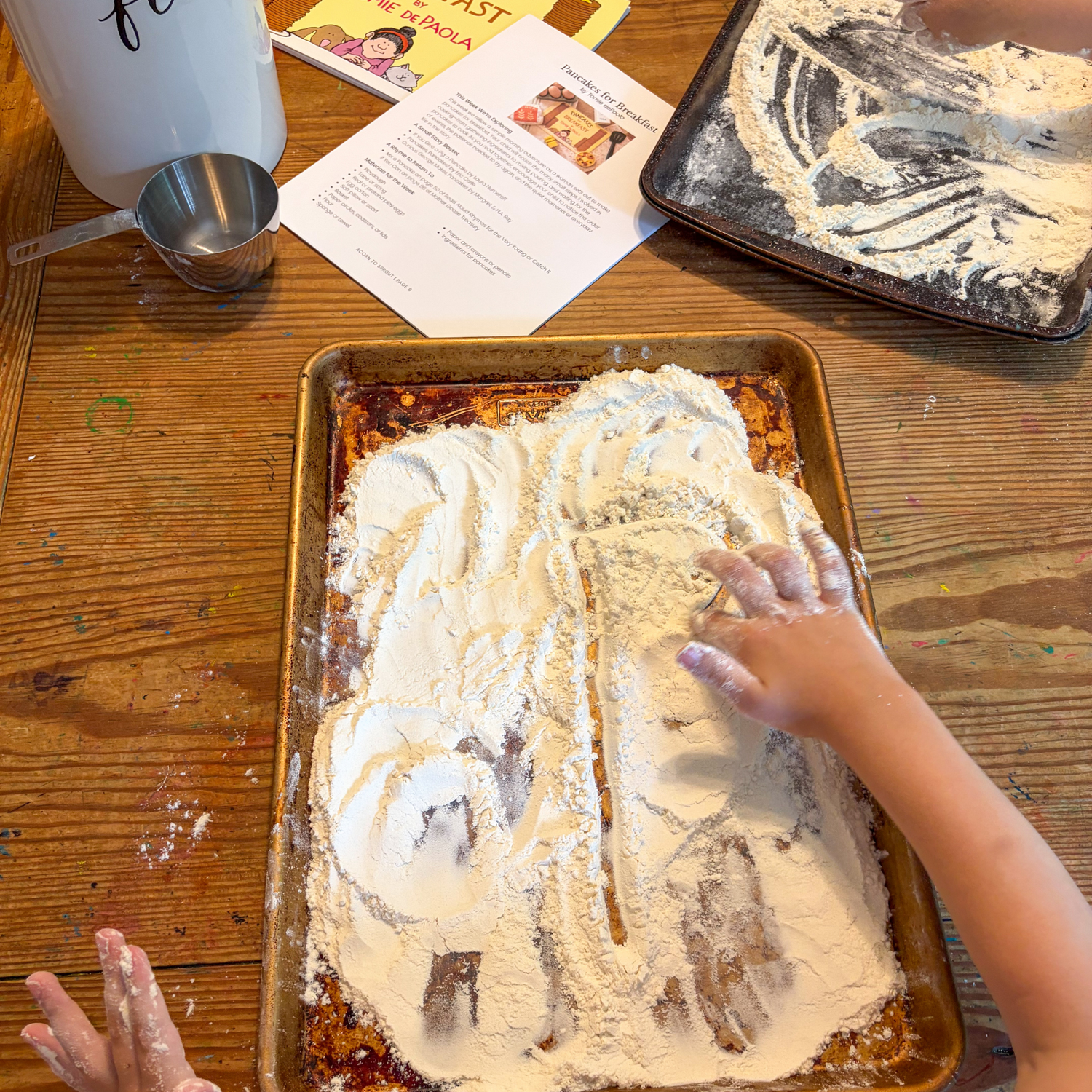 Child drawing in flour during a hands-on activity inspired by Pancakes for Breakfast.