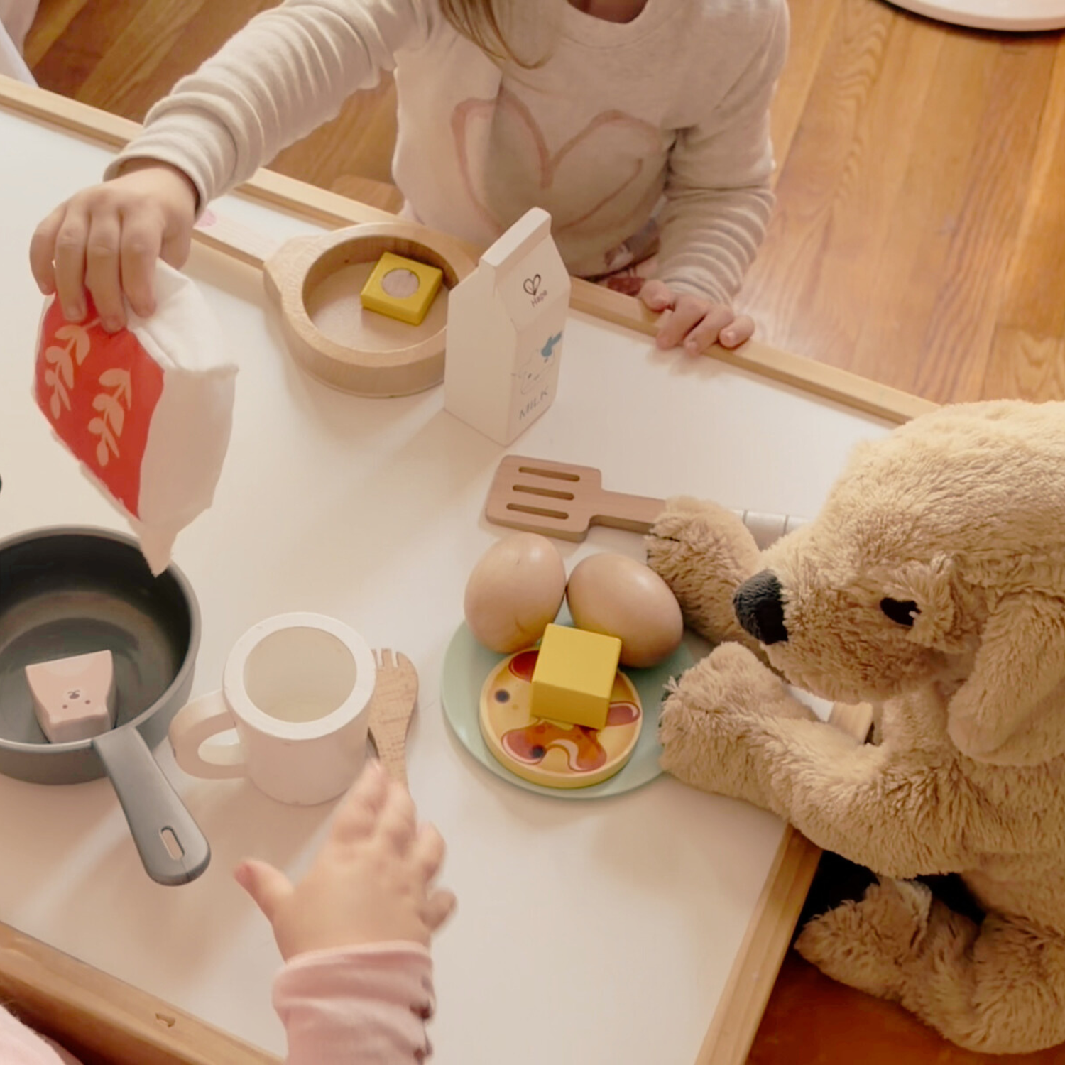 Children engaging in hands-on pretend play with wooden pancake toys inspired by Pancakes for Breakfast as part of a gentle homeschool activity.