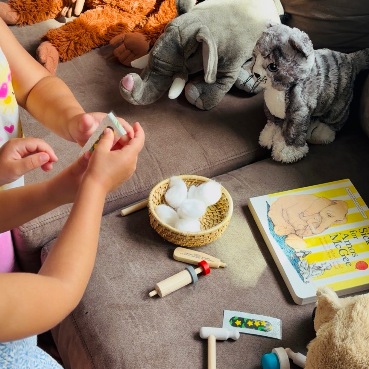 Children caring for stuffed animals with pretend medical supplies during play inspired by A Sick Day for Amos McGee.