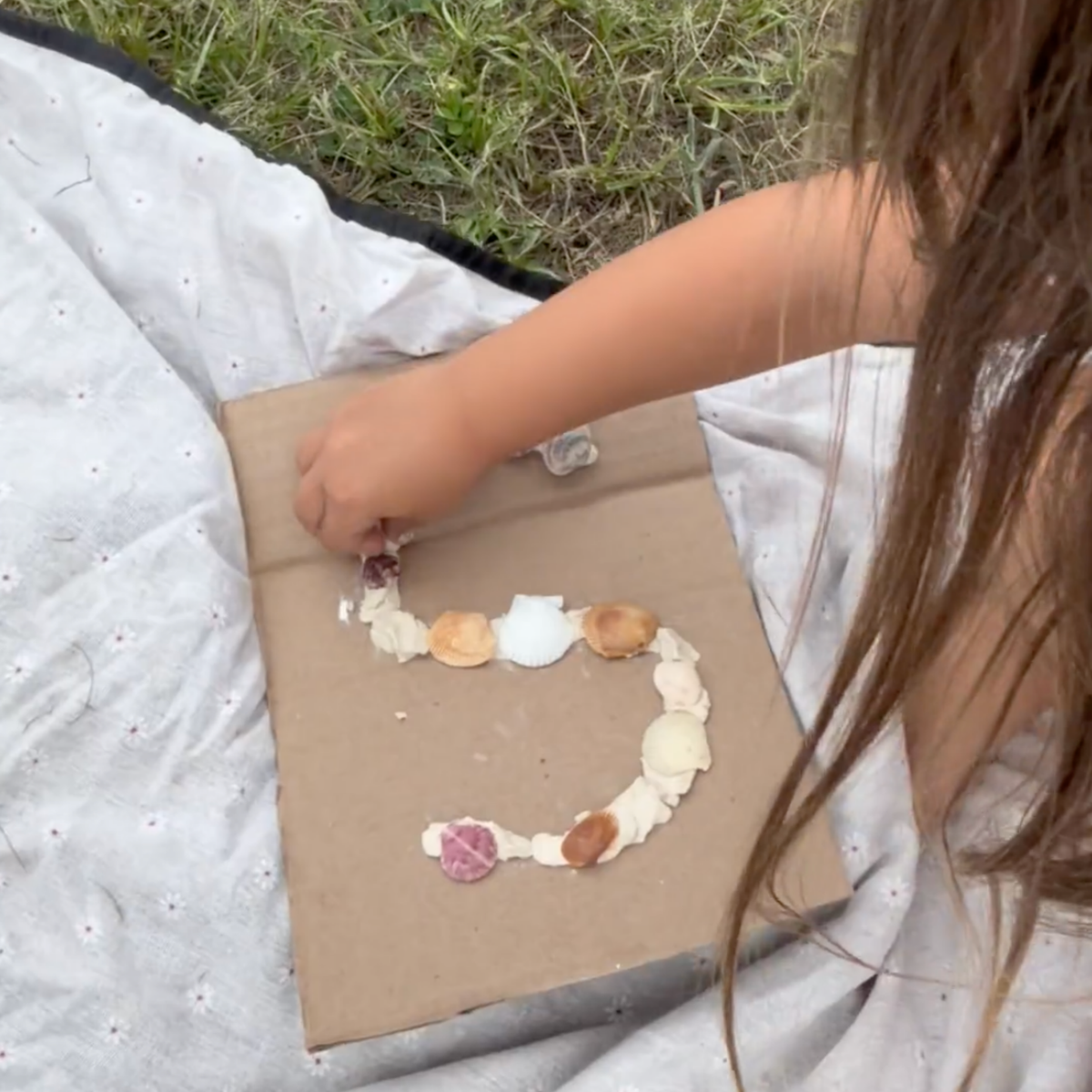 Child arranging seashells into a letter shape during a hands-on activity inspired by The Snail and the Whale.