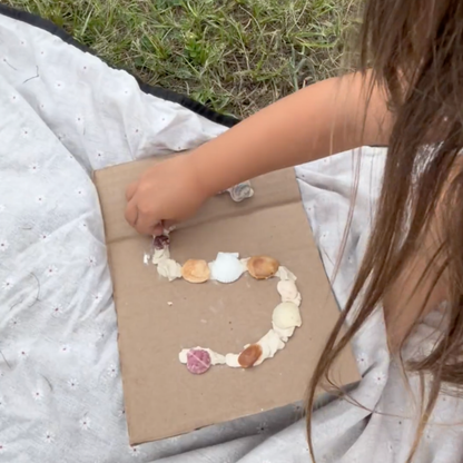 Child arranging seashells into a letter shape during a hands-on activity inspired by The Snail and the Whale.