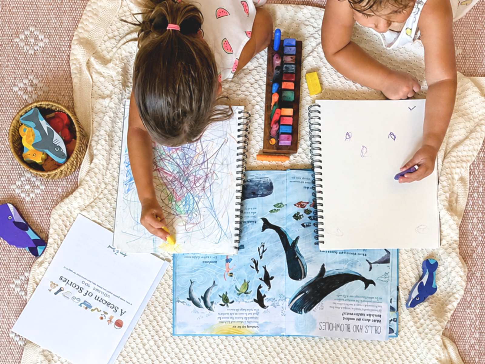 Two young children drawing beside The Snail and the Whale and an Acorn to Sprout story-led learning guide.